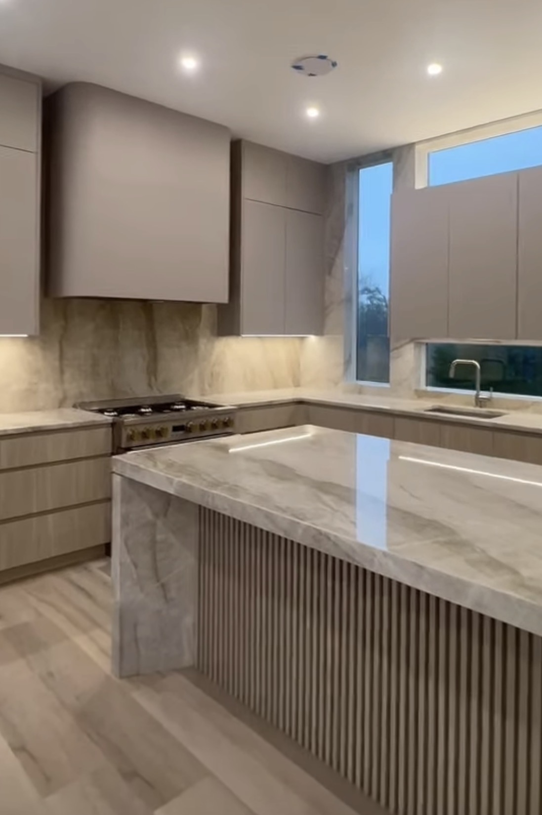 Finished designer kitchen with light stone surfaces and matching full-height backsplash